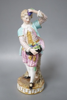 A 19th century Meissen figure of a boy holding grapes to his head, his hat full of grapes, wearing a crinoline scarf and shirt cuffs, crossed swords in blue, incise letters and numbers 17cm